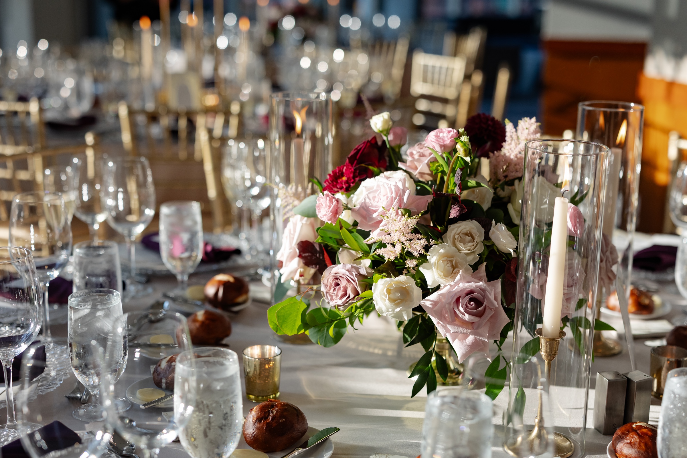 Designed wedding reception table with place settings and floral details and large greenery and blush rose flowers in a hanging floral installation 
