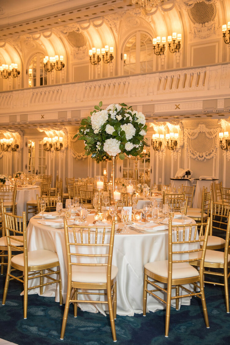 Ballroom reception with white floral centerpieces and gold chairs from Traci’s event archive